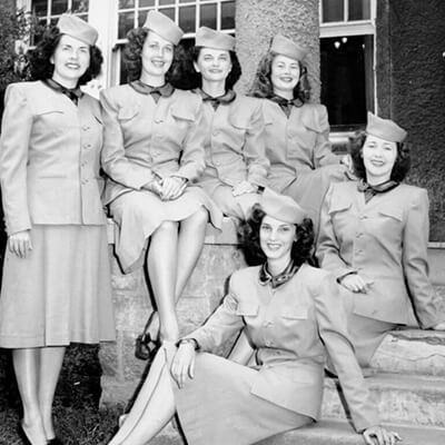 6 women in uniforms sit on a staircase in 1947.