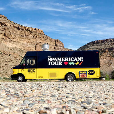 The SPAMERICAN Tour truck in front of mountains.